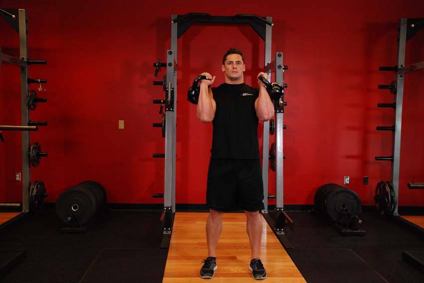 Demonstration of Alternating Kettlebell Press exercise showing proper form and technique