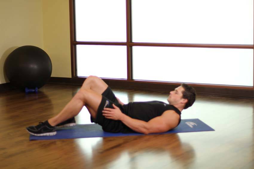 Demonstration of Ankle On The Knee exercise showing proper form and technique