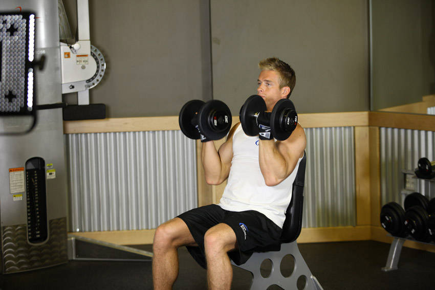 Demonstration of Arnold Dumbbell Press exercise showing proper form and technique