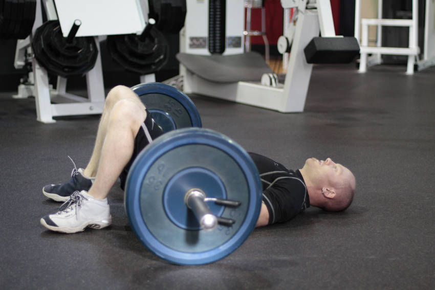 Demonstration of Barbell Glute Bridge exercise showing proper form and technique