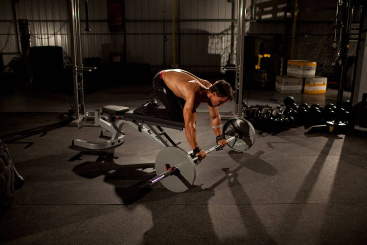 Demonstration of Barbell Rollout from Bench exercise showing proper form and technique
