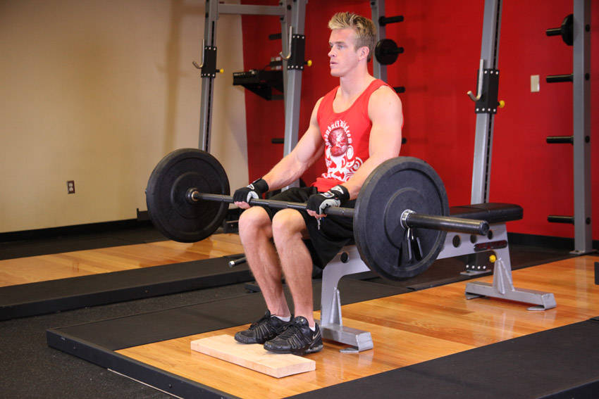 Demonstration of Barbell Seated Calf Raise exercise showing proper form and technique