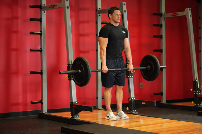 Demonstration of Barbell Shrug exercise showing proper form and technique