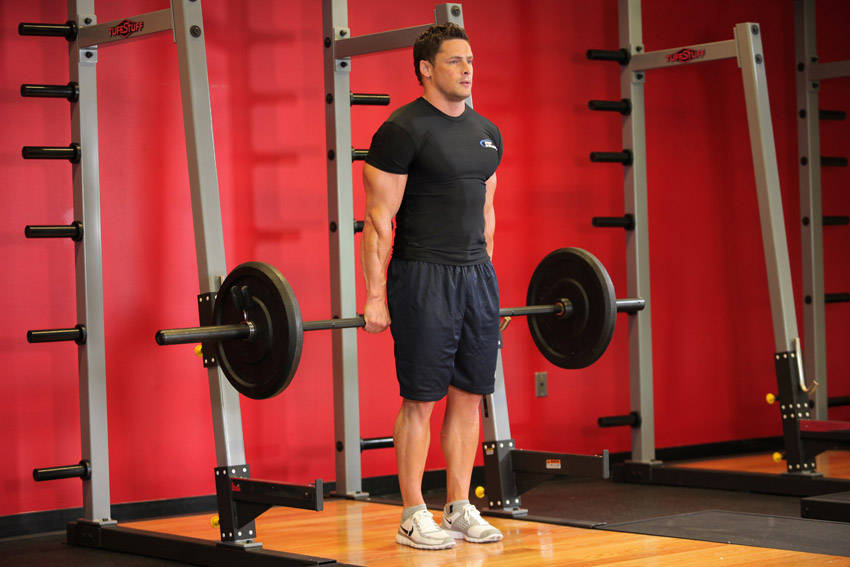 Demonstration of Barbell Shrug Behind The Back exercise showing proper form and technique