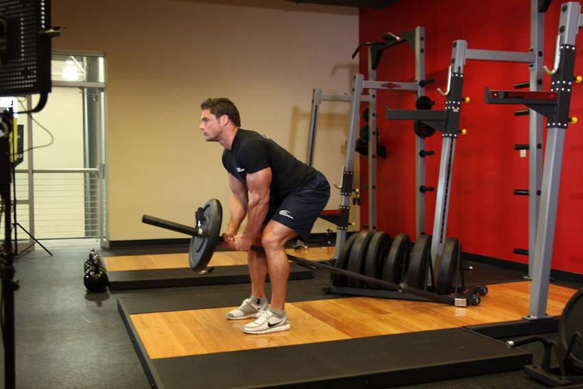 Demonstration of Bent Over Two-Arm Long Bar Row exercise showing proper form and technique