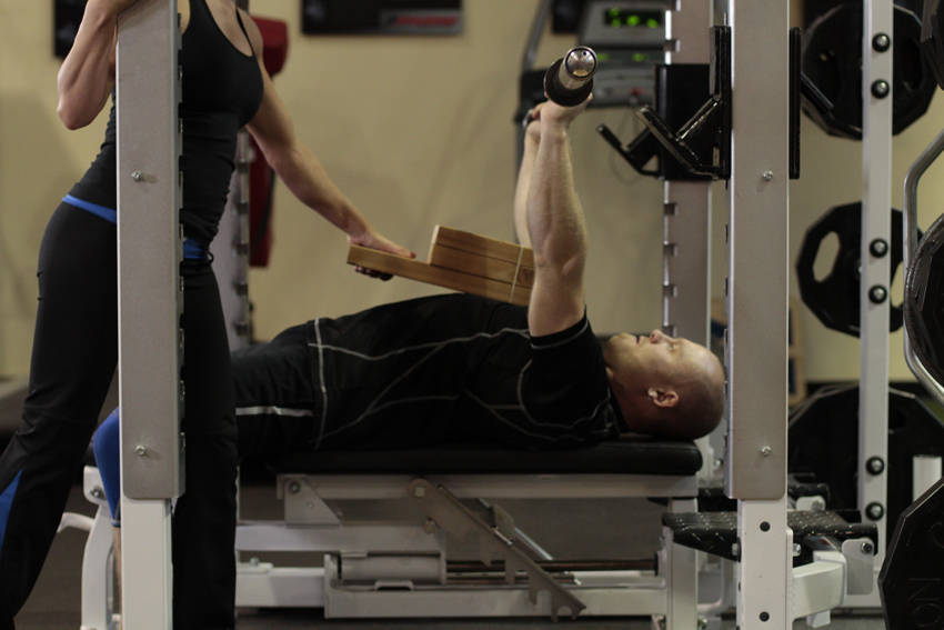 Demonstration of Board Press exercise showing proper form and technique