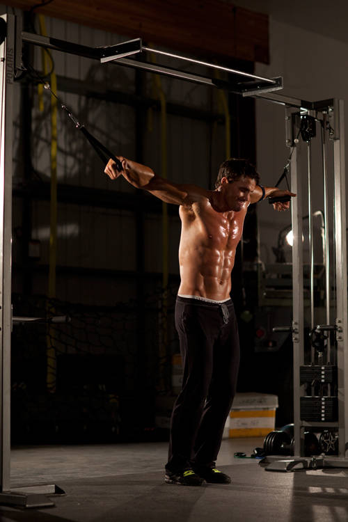 Demonstration of Cable Iron Cross exercise showing proper form and technique