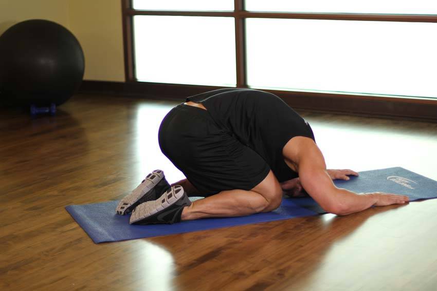 Demonstration of Child's Pose exercise showing proper form and technique