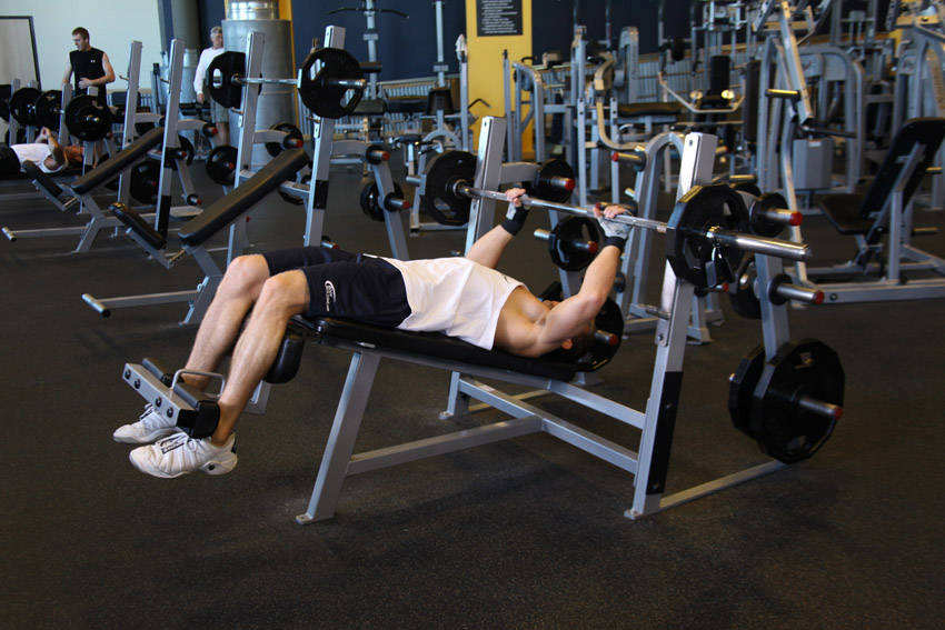 Demonstration of Decline Barbell Bench Press exercise showing proper form and technique