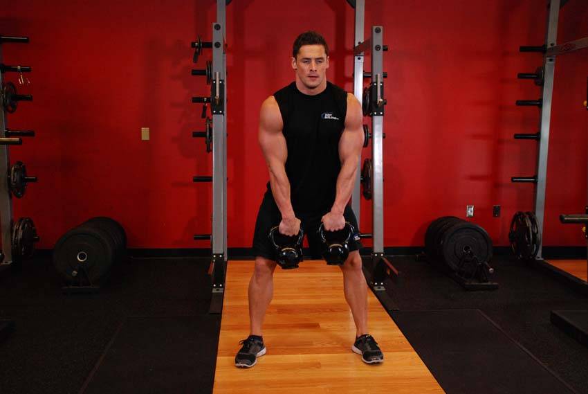 Demonstration of Double Kettlebell Alternating Hang Clean exercise showing proper form and technique