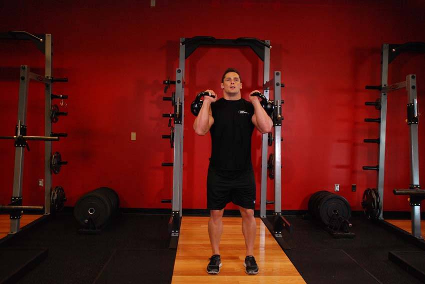 Demonstration of Double Kettlebell Push Press exercise showing proper form and technique