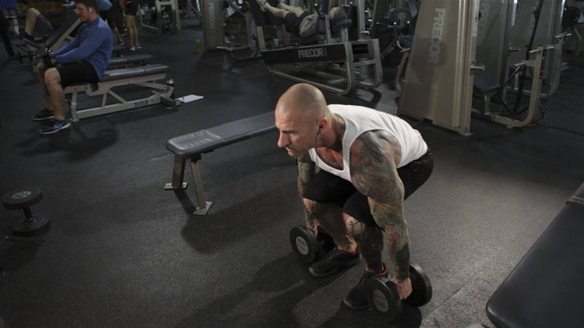 Demonstration of Dumbbell Clean exercise showing proper form and technique