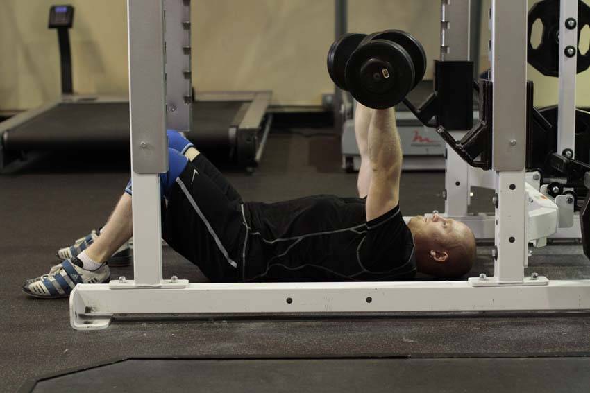 Demonstration of Dumbbell Floor Press exercise showing proper form and technique