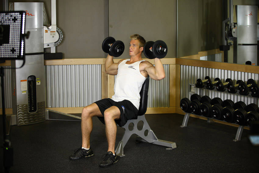 Demonstration of Dumbbell Shoulder Press exercise showing proper form and technique
