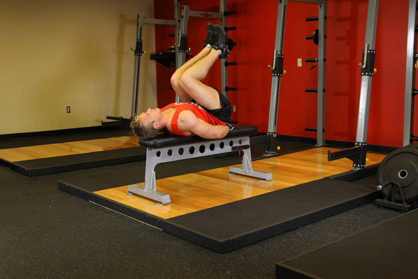 Demonstration of Flat Bench Leg Pull-In exercise showing proper form and technique