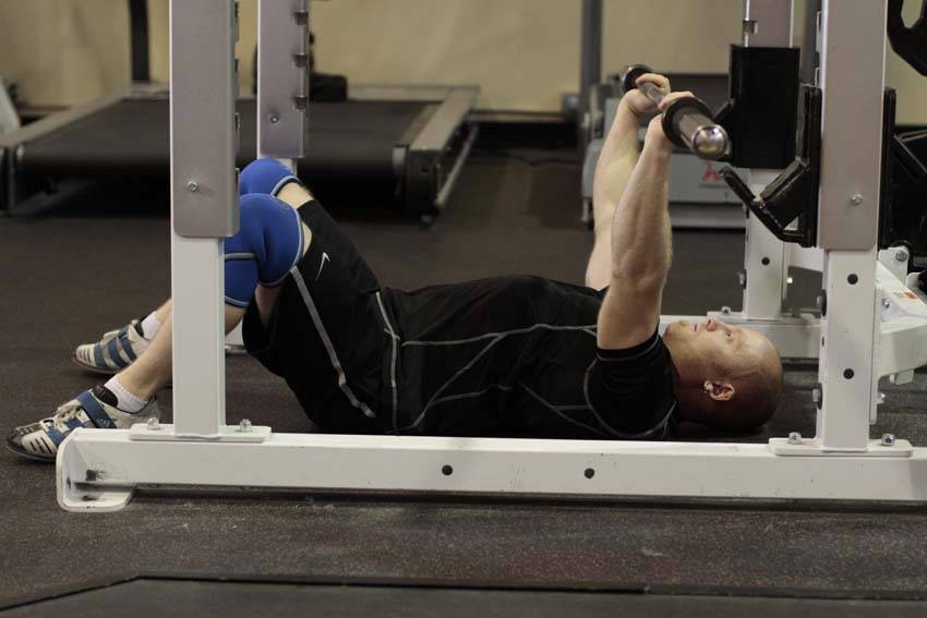 Demonstration of Floor Press exercise showing proper form and technique