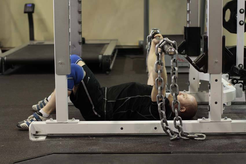 Demonstration of Floor Press with Chains exercise showing proper form and technique