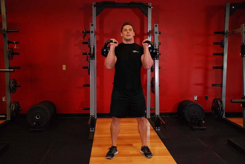 Demonstration of Kettlebell Thruster exercise showing proper form and technique
