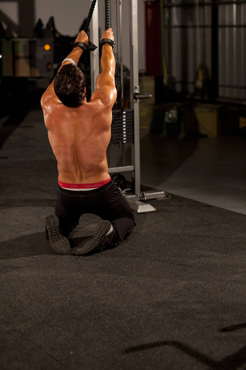 Demonstration of Kneeling High Pulley Row exercise showing proper form and technique