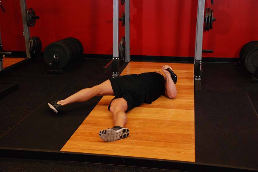 Demonstration of Leg-Over Floor Press exercise showing proper form and technique