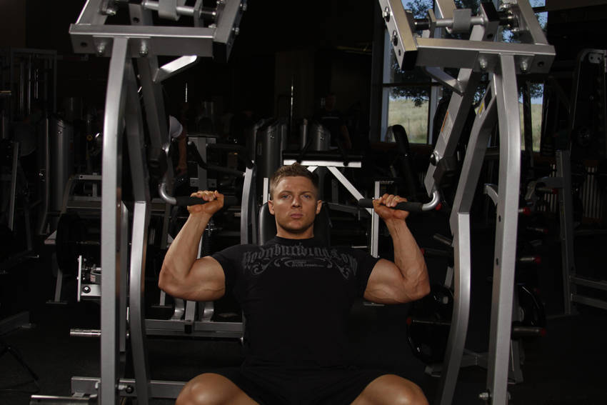 Demonstration of Leverage Shoulder Press exercise showing proper form and technique