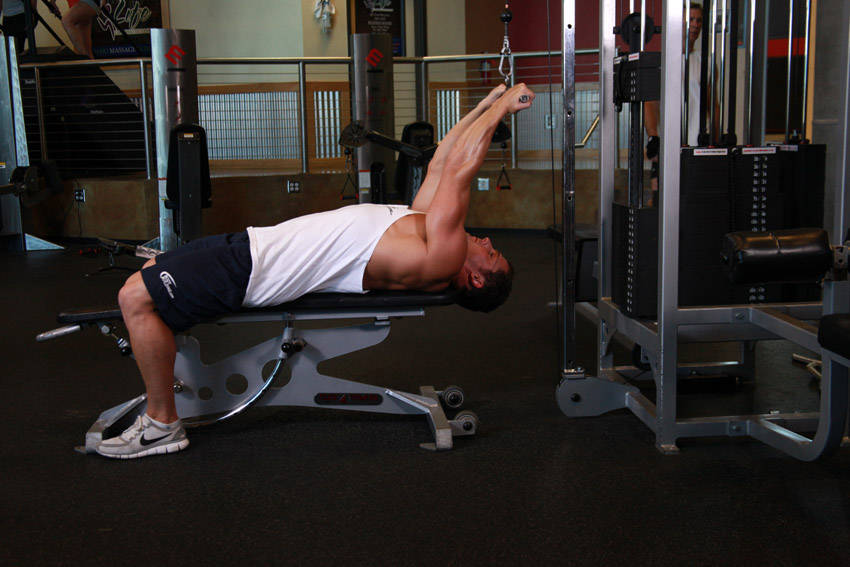 Demonstration of Lying Close-Grip Bar Curl On High Pulley exercise showing proper form and technique