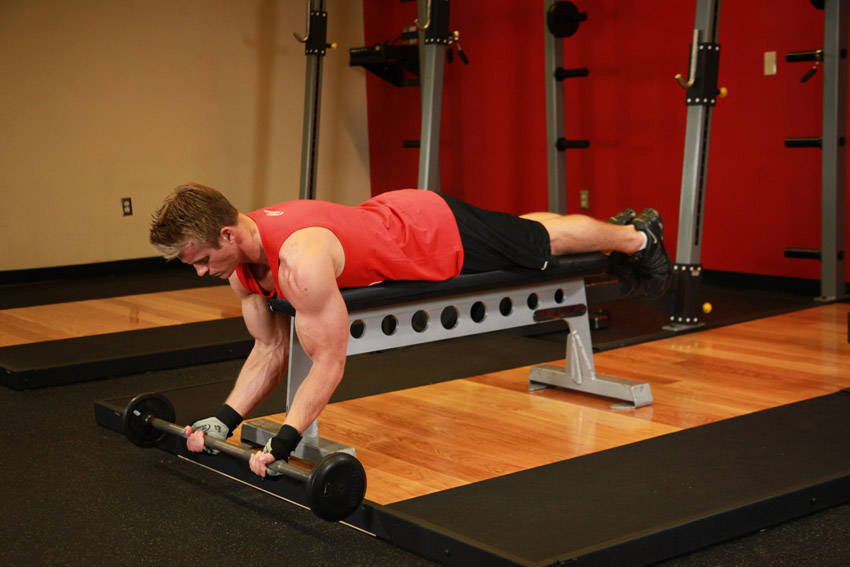 Demonstration of Lying High Bench Barbell Curl exercise showing proper form and technique