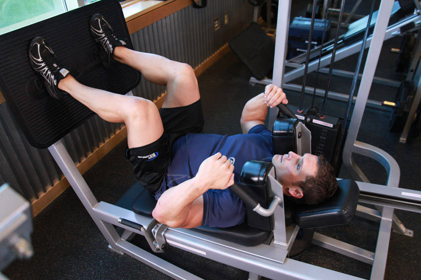 Demonstration of Lying Machine Squat exercise showing proper form and technique
