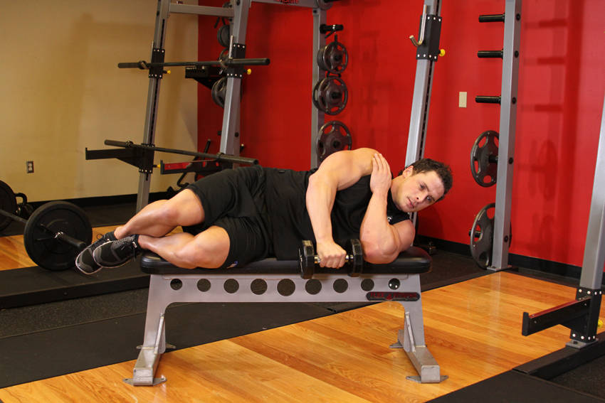 Demonstration of Lying One-Arm Lateral Raise exercise showing proper form and technique