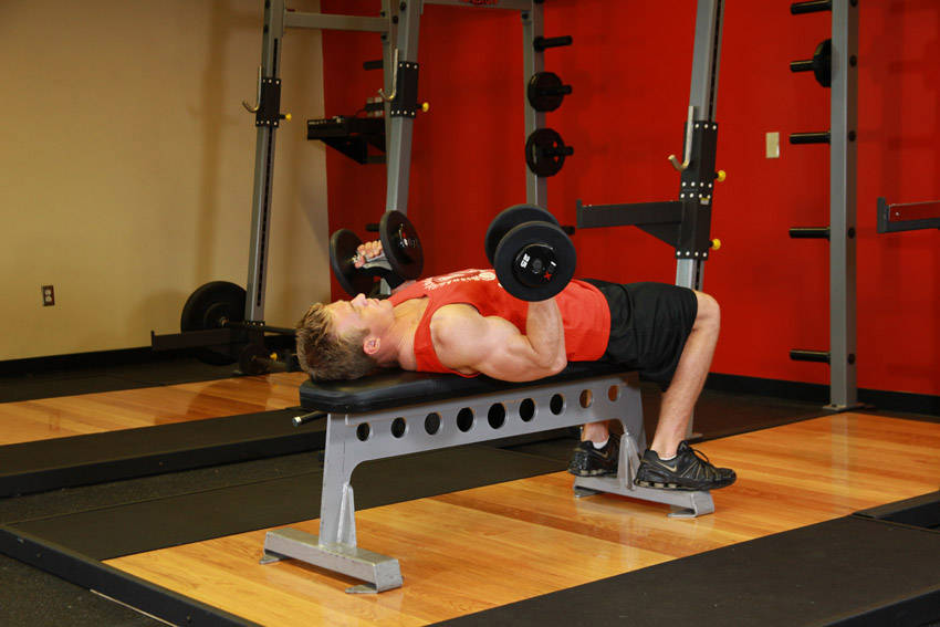 Demonstration of Lying Supine Dumbbell Curl exercise showing proper form and technique