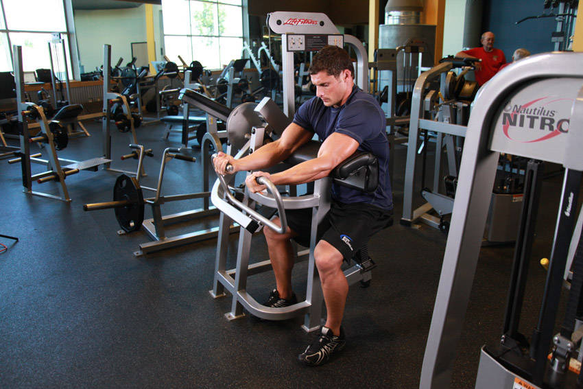 Demonstration of Machine Preacher Curls exercise showing proper form and technique