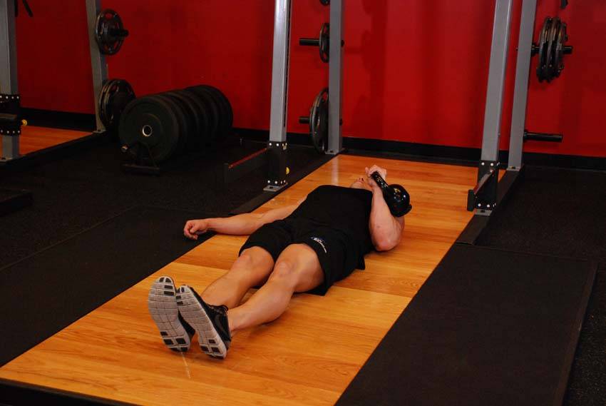 Demonstration of One-Arm Kettlebell Floor Press exercise showing proper form and technique