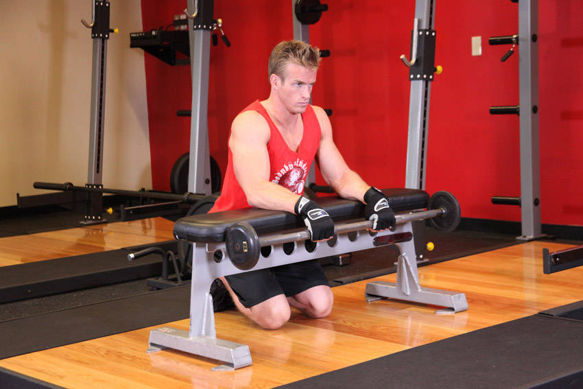 Demonstration of Palms-Down Wrist Curl Over A Bench exercise showing proper form and technique