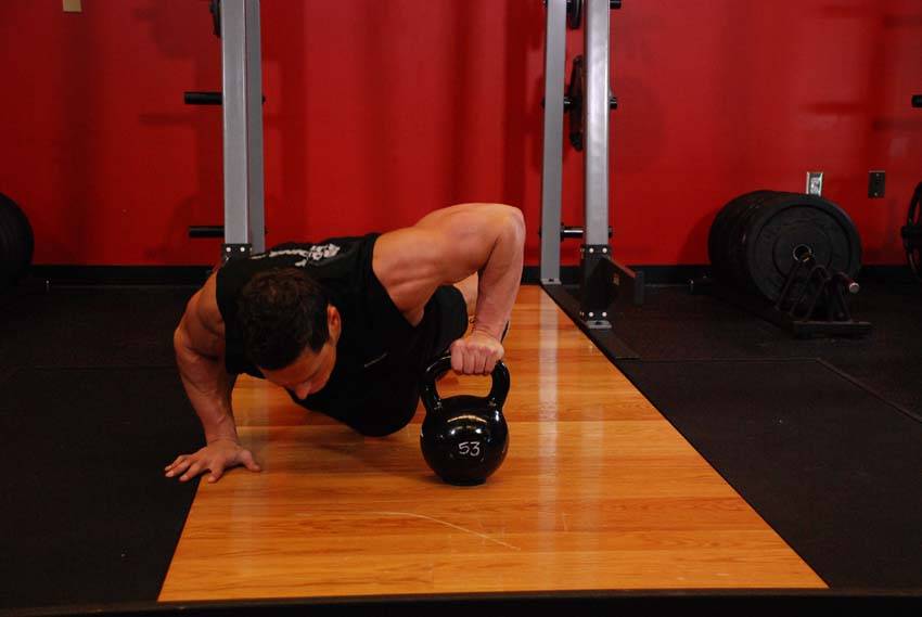 Demonstration of Plyo Kettlebell Pushups exercise showing proper form and technique