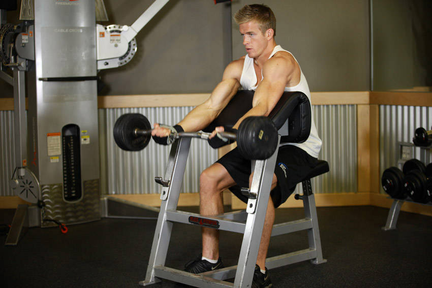 Demonstration of Preacher Curl exercise showing proper form and technique