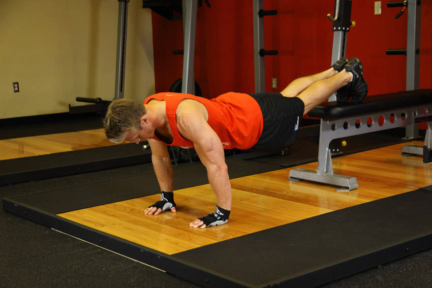 Demonstration of Push-Ups With Feet Elevated exercise showing proper form and technique