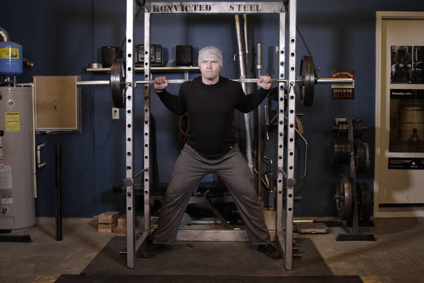 Demonstration of Reverse Band Power Squat exercise showing proper form and technique