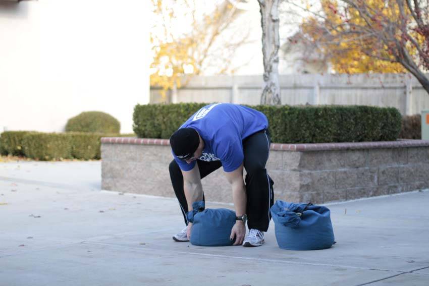 Demonstration of Sandbag Load exercise showing proper form and technique