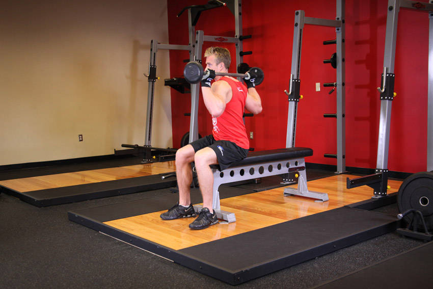 Demonstration of Seated Barbell Twist exercise showing proper form and technique