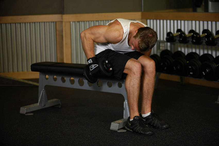 Demonstration of Seated Bent-Over One-Arm Dumbbell Triceps Extension exercise showing proper form and technique