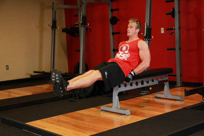 Demonstration of Seated Flat Bench Leg Pull-In exercise showing proper form and technique