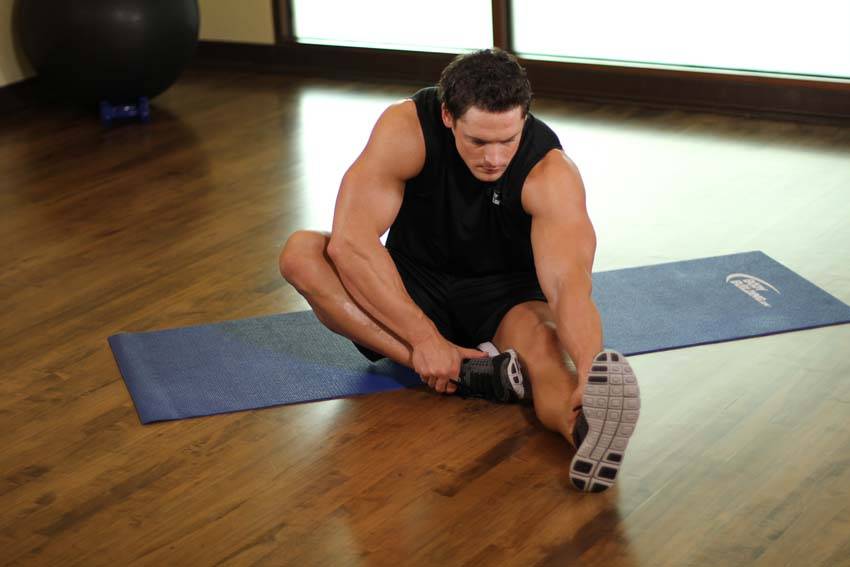 Demonstration of Seated Floor Hamstring Stretch exercise showing proper form and technique