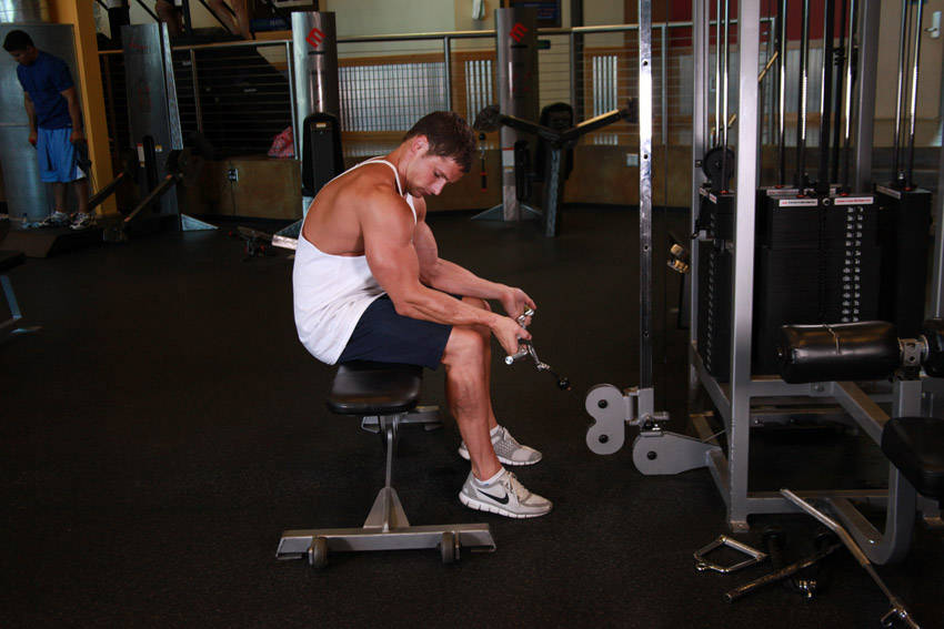 Demonstration of Seated Two-Arm Palms-Up Low-Pulley Wrist Curl exercise showing proper form and technique
