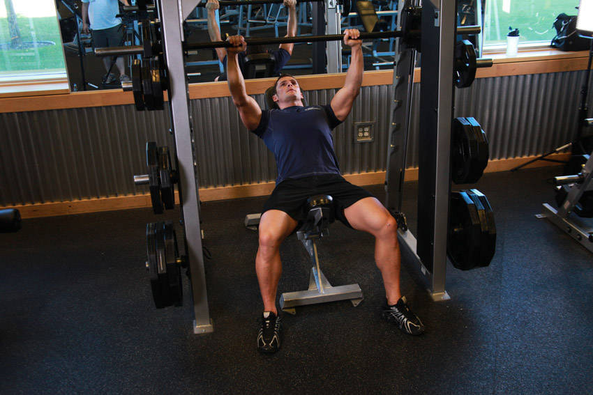 Demonstration of Smith Incline Shoulder Raise exercise showing proper form and technique