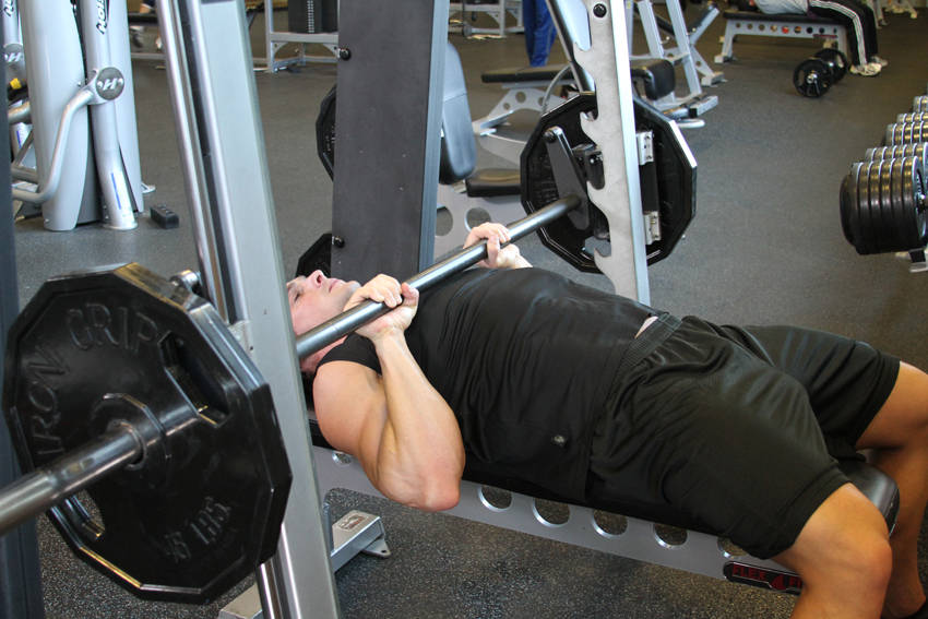 Demonstration of Smith Machine Close-Grip Bench Press exercise showing proper form and technique