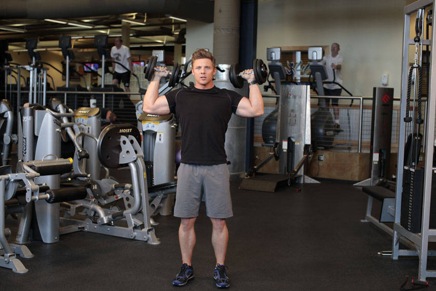 Demonstration of Standing Alternating Dumbbell Press exercise showing proper form and technique