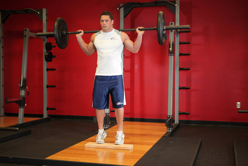 Demonstration of Standing Barbell Calf Raise exercise showing proper form and technique