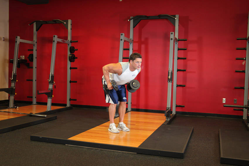 Demonstration of Standing Bent-Over Two-Arm Dumbbell Triceps Extension exercise showing proper form and technique
