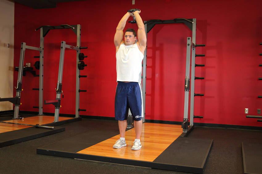 Demonstration of Standing Dumbbell Triceps Extension exercise showing proper form and technique