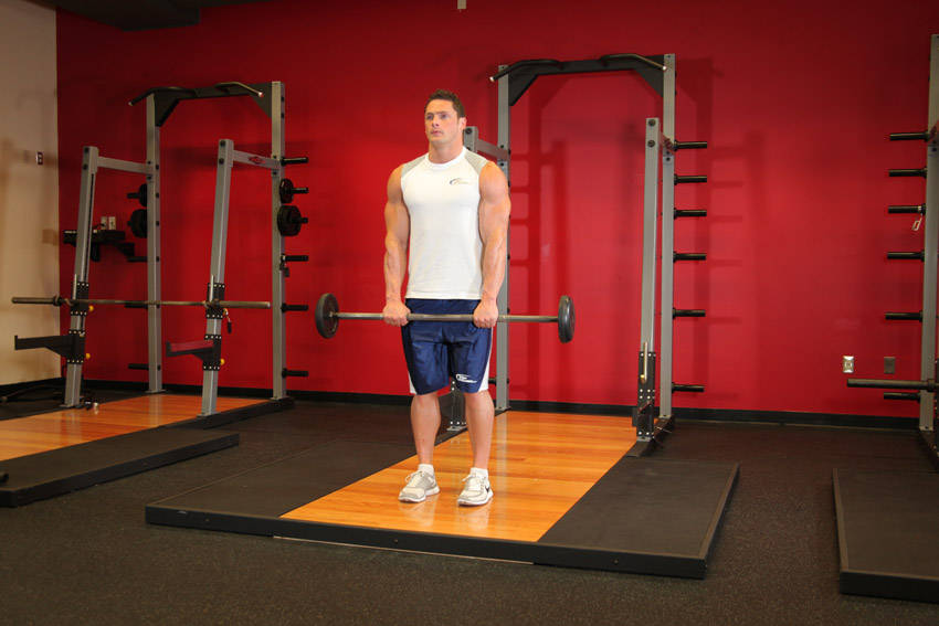 Demonstration of Standing Front Barbell Raise Over Head exercise showing proper form and technique